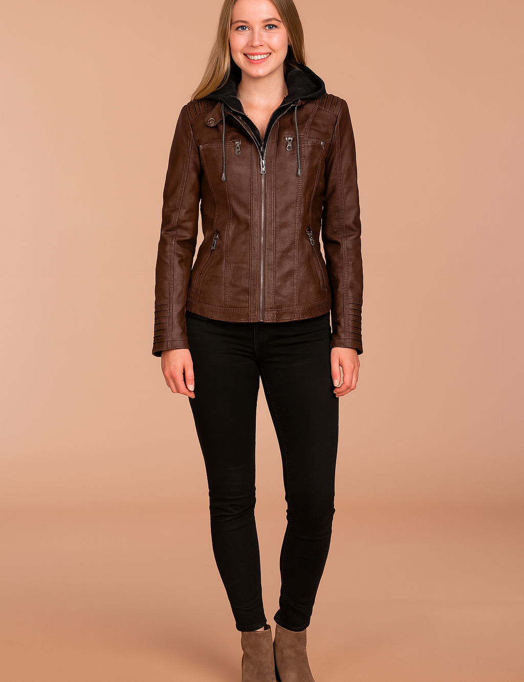Brown hooded leather jacket with zip front, stitched panel detailing, and multiple zippered pockets, styled with black fitted pants and taupe ankle boots