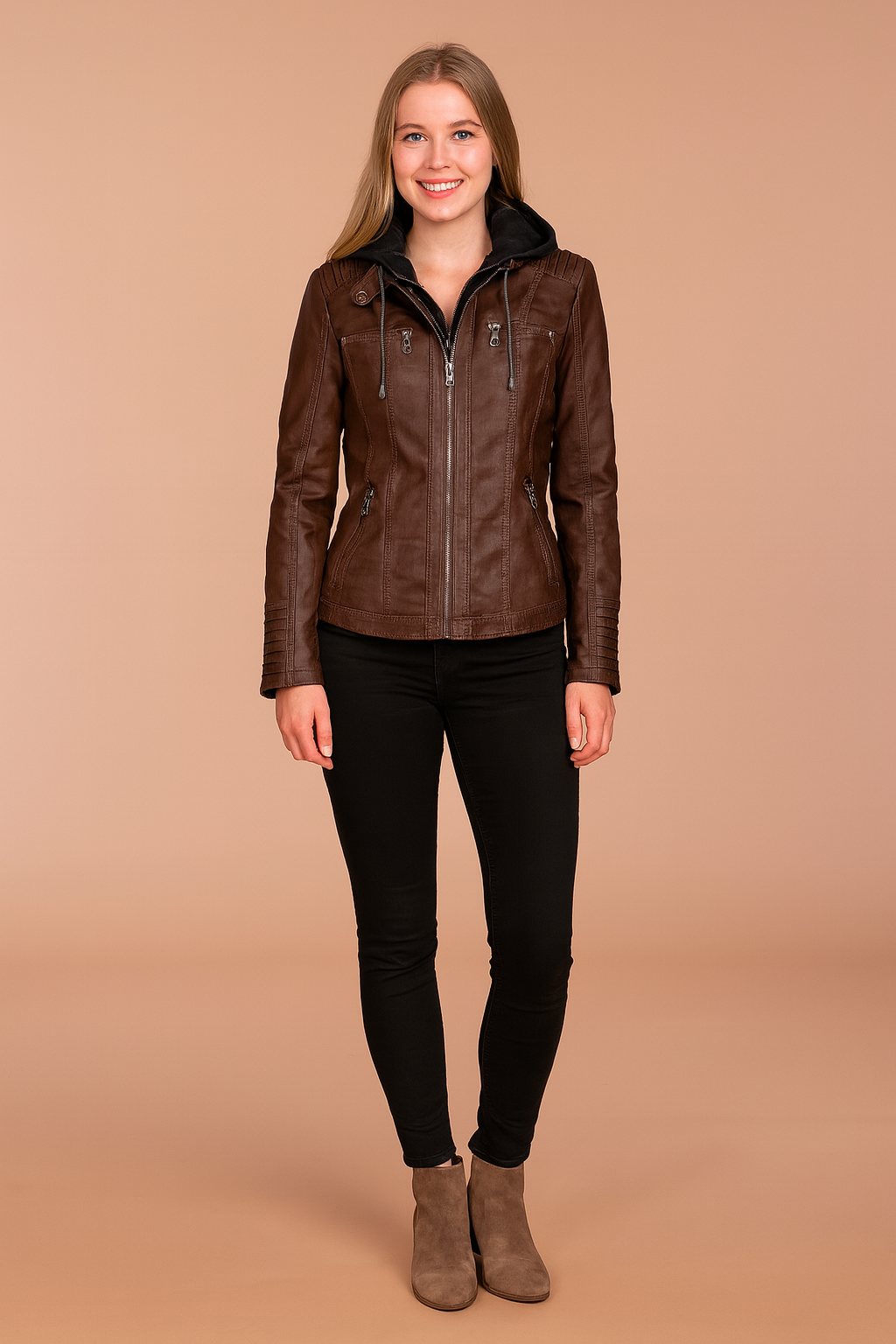 Brown hooded leather jacket with zip front, stitched panel detailing, and multiple zippered pockets, styled with black fitted pants and taupe ankle boots
