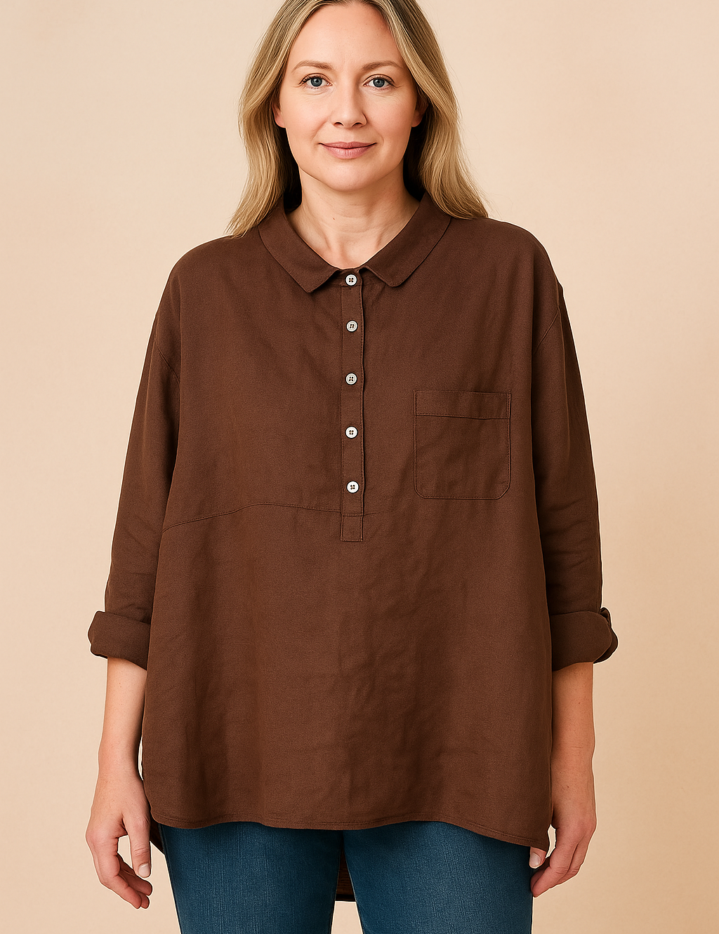 Woman wearing relaxed brown linen shirt with rolled sleeves and collar, paired with blue jeans, on a warm sand pastel background.