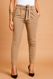 Tailored brown paperbag pants with high waist, pleats, and belt tie, styled with side pockets and tapered legs for a polished everyday look.