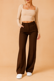 High-waisted wide-leg brown tailored pants featuring clean seam lines and a flat front design, paired with a beige ribbed square-neck crop top and white sneakers for a chic modern silhouette.

