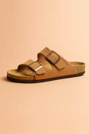  suede slip-on sandal featuring a contoured cork footbed and two wide straps with oversized brown buckles for adjustable comfort.