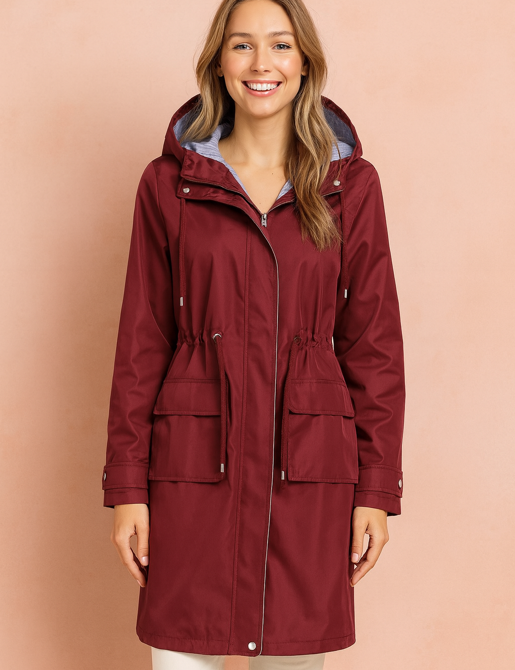 Burgundy waterproof hooded raincoat with adjustable drawstring waist, front zipper closure, flap pockets, and striped lining detail.