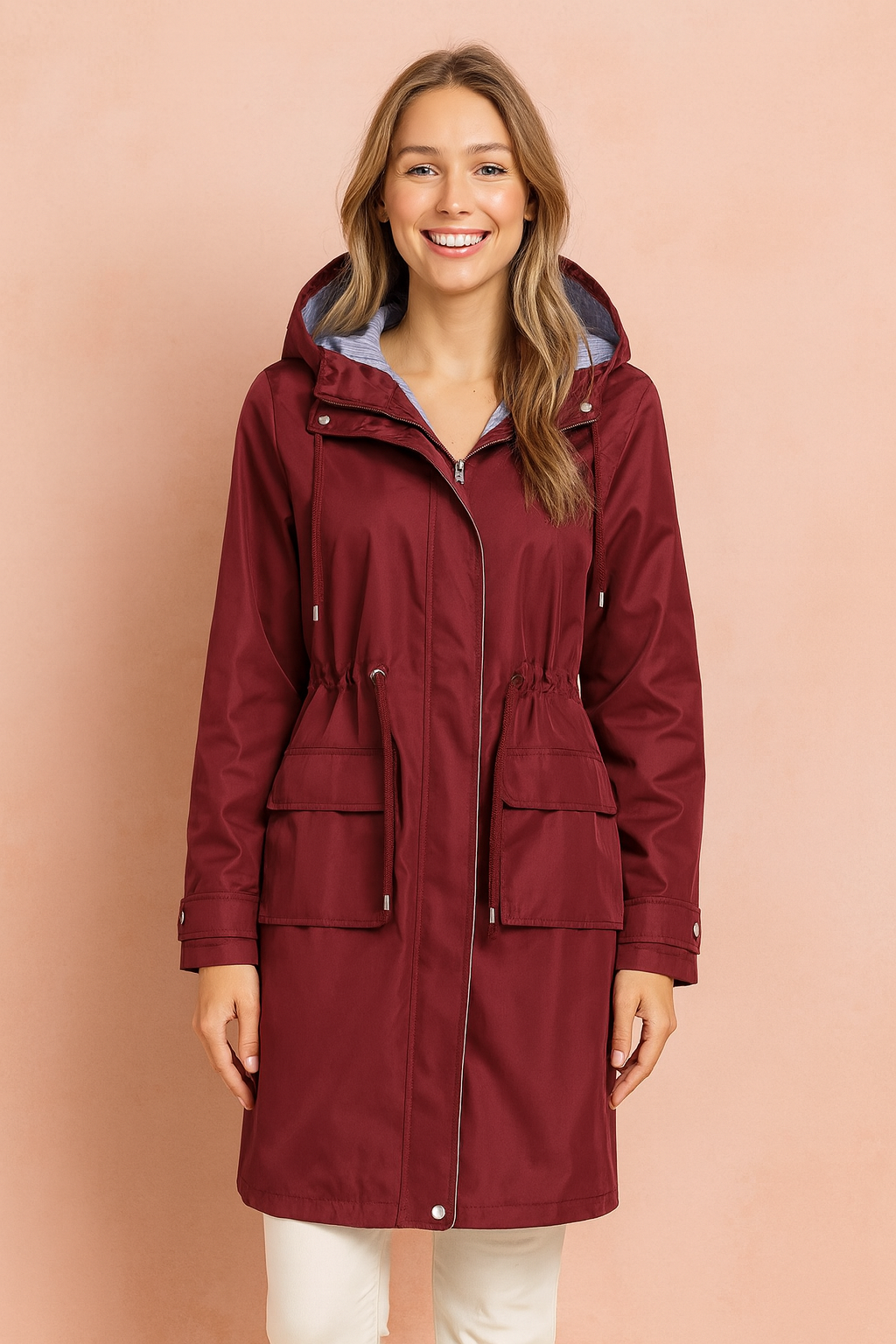 Burgundy waterproof hooded raincoat with adjustable drawstring waist, front zipper closure, flap pockets, and striped lining detail.