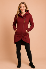 Burgundy asymmetrical zip hoodie with curved hem, front pockets, ribbed cuffs, and patterned drawstrings, styled with black skinny jeans and ankle boots