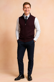 Burgundy zip-up knit sweater vest with front pockets, paired with a white dress shirt, black tie, navy trousers, and black leather shoes.