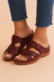 Burgundy open-toe leather slide sandals with crisscross perforated straps, topstitched detailing, and a contoured low wedge sole.