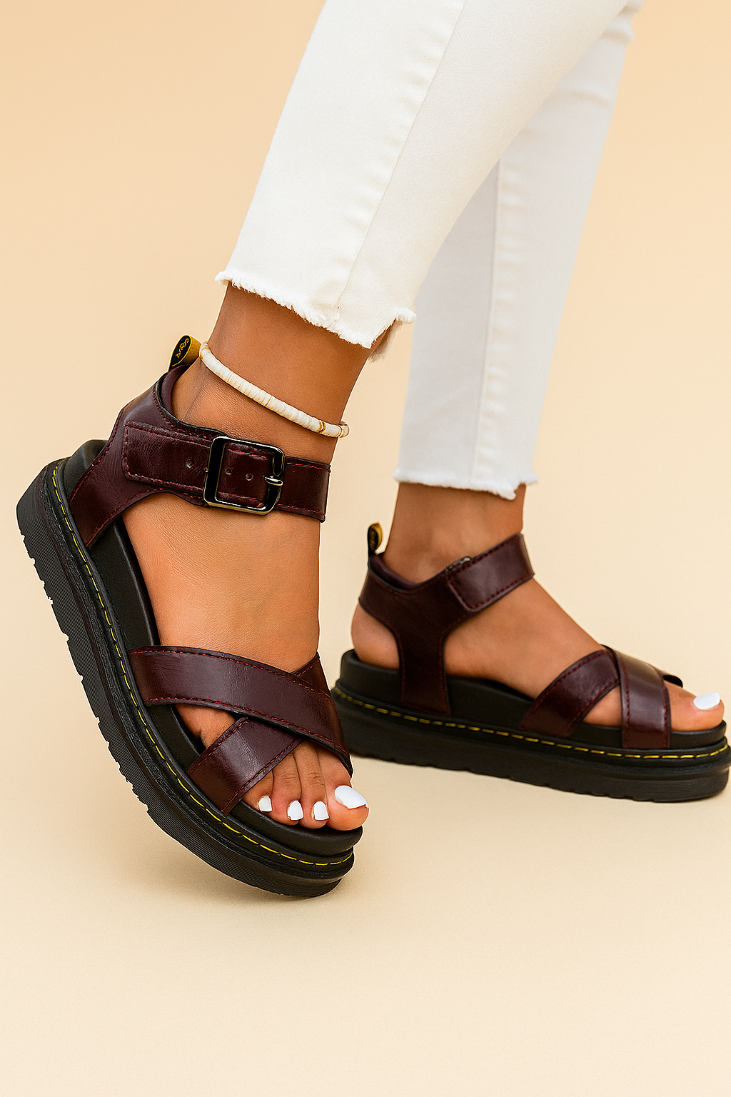 Burgundy leather platform sandals with cross-over glossy straps, a thick black sole with yellow stitching, and an adjustable square buckle ankle strap.