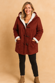 Burgundy toggle coat with white faux shearling lining, paired with black slim-fit jeans and taupe ankle boots.