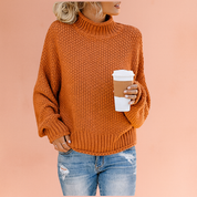 Burnt-orange chunky knit turtleneck sweater with ribbed cuffs and hem, paired with distressed light blue jeans.