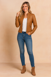 Camel brown faux leather fitted jacket with zipper pockets, styled with a white T-shirt, blue slim-fit jeans, and taupe suede ankle boots