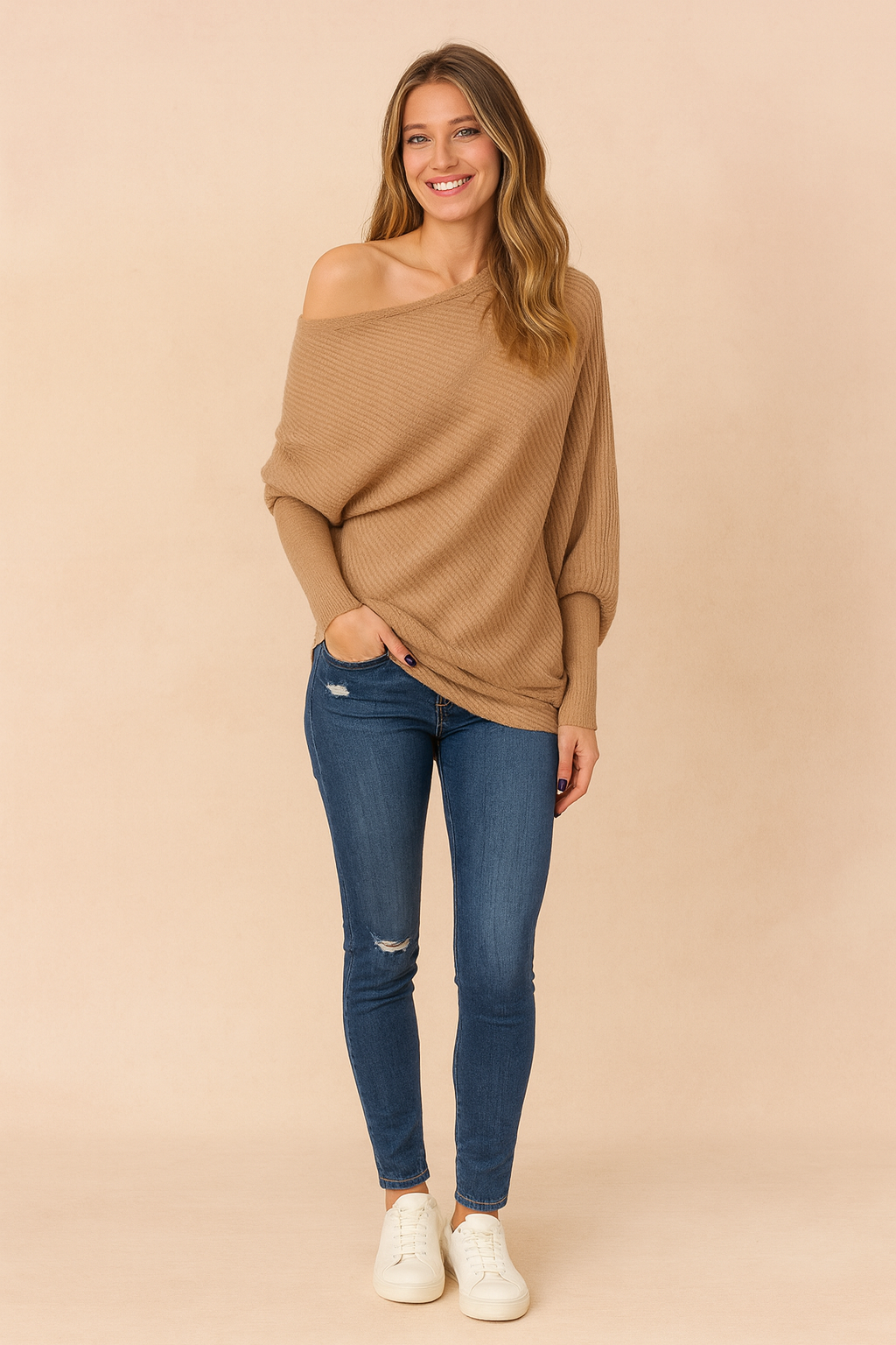 Camel ribbed knit off-the-shoulder sweater paired with distressed blue skinny jeans and classic white lace-up sneakers for a chic casual style.