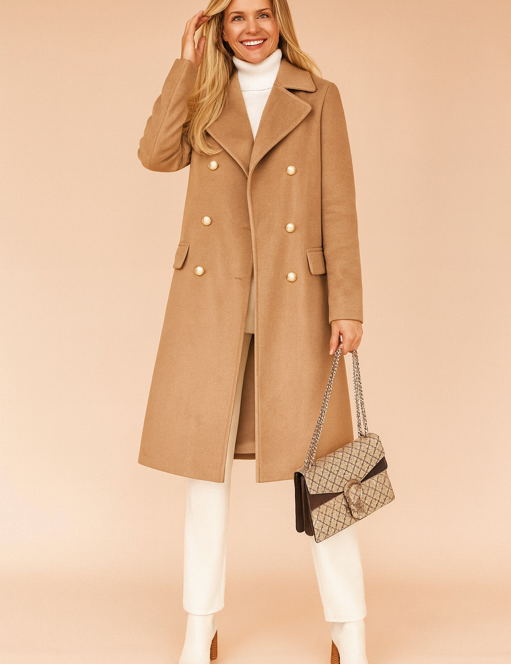 Camel double-breasted wool coat with gold-toned buttons, paired with a white turtleneck, cream trousers, and white ankle boots, accessorized with a beige patterned handbag.