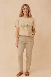 Oversized beige graphic T-shirt with a "Capri" lemon branch print and cursive script, styled with casual beige jeans and brown sandals.