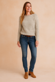 Cream knit sweater with subtle gray speckled pattern, paired with fitted dark blue jeans and tan suede ankle boots.