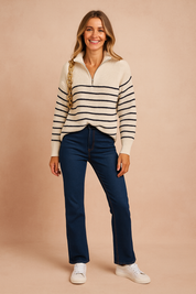 Cream ribbed half-zip sweater with navy horizontal stripes, paired with dark blue straight-leg jeans and white lace-up sneakers.