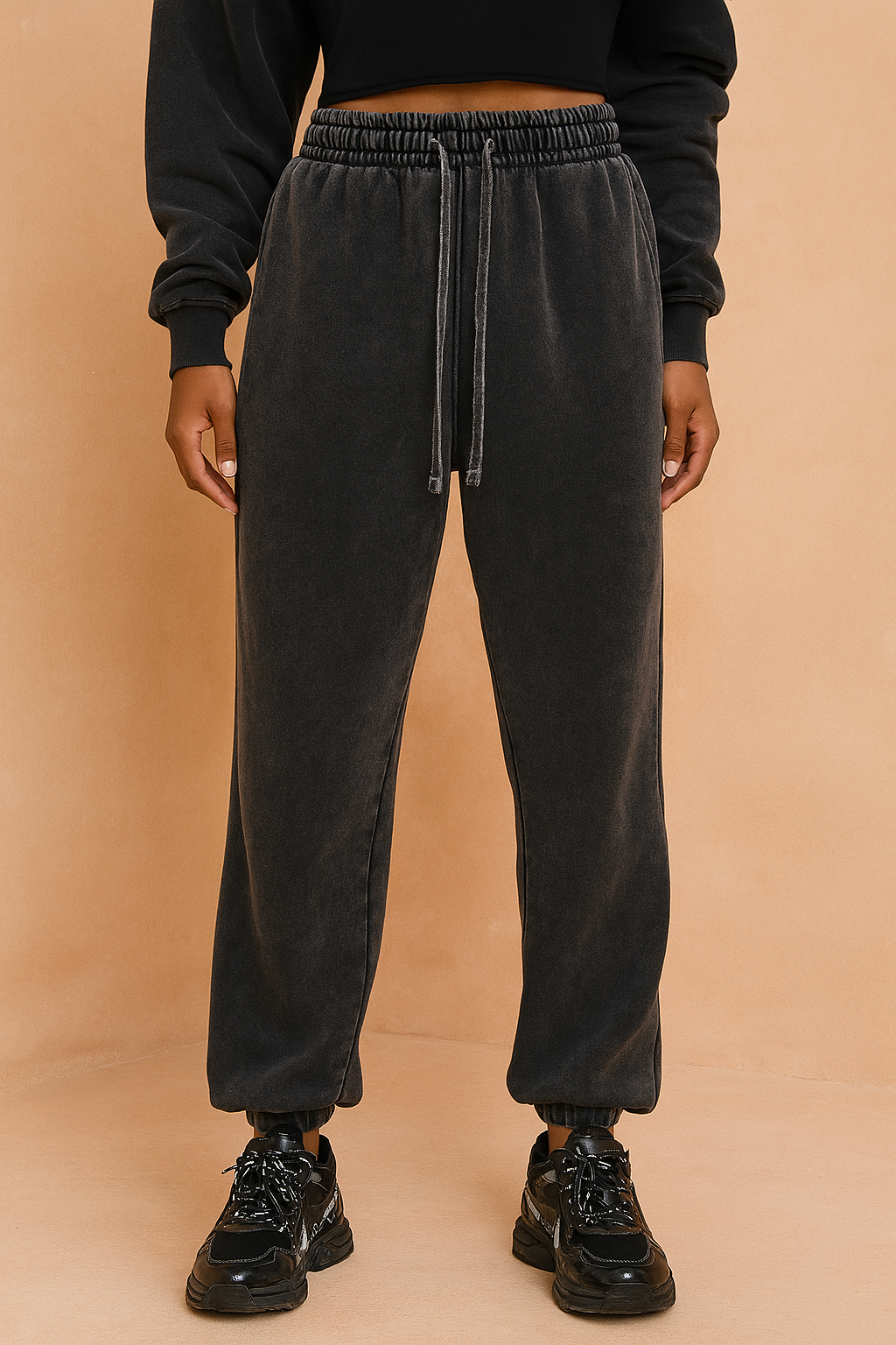 Washed charcoal black sweatpants with a relaxed straight-leg fit, elastic cuffs, long tonal drawstrings, and subtle vintage fade detailing, paired with chunky black sneakers.