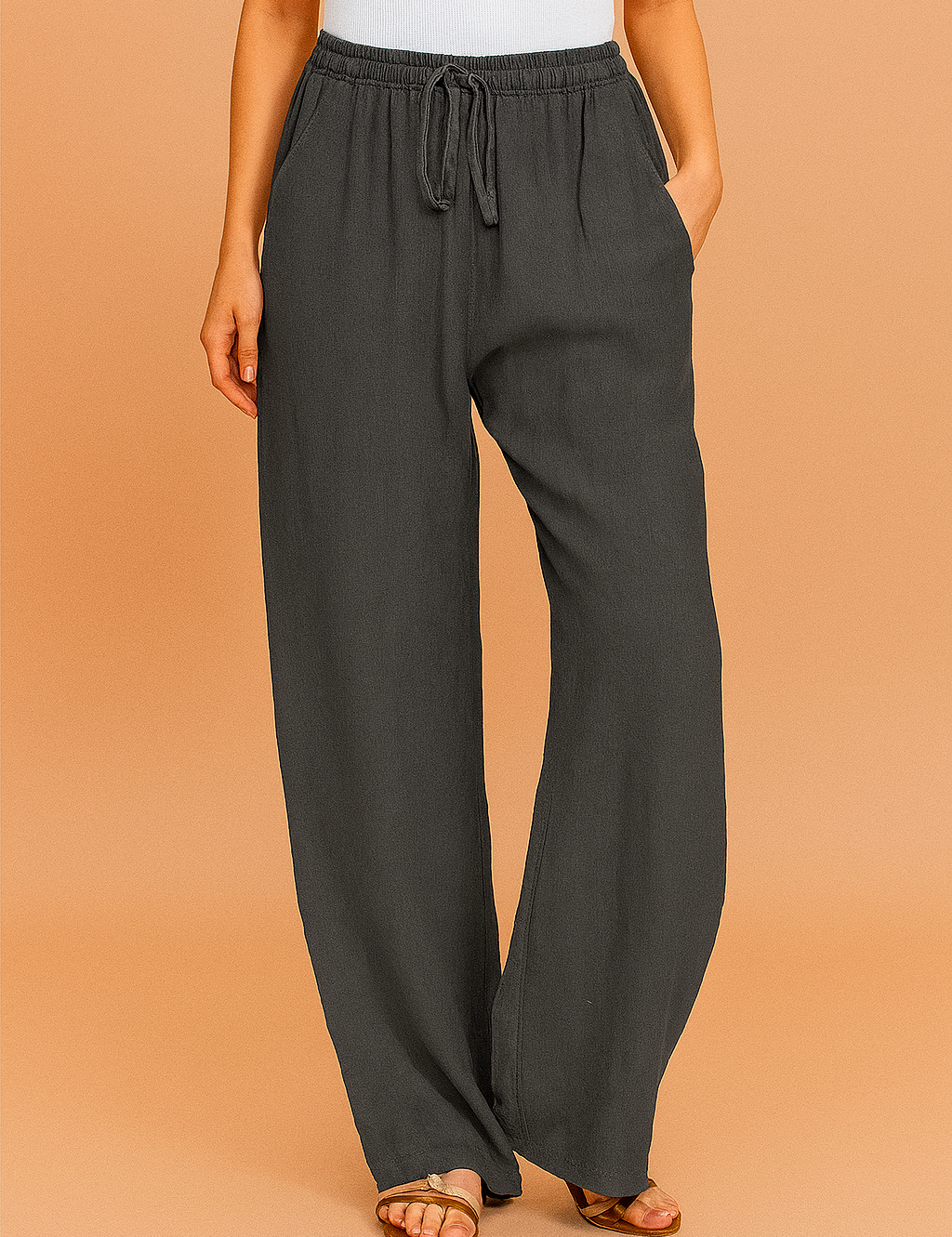 Charcoal gray linen wide-leg pants with a relaxed silhouette, drawstring elastic waistband, and side pockets, styled with flat tan sandals.
