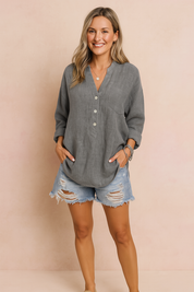 Loose-fit charcoal gray linen blouse with three white buttons and a chest pocket, paired with distressed light-wash denim shorts.