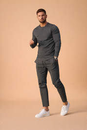 Slim-fit charcoal gray long-sleeve stretch shirt paired with matching tapered drawstring trousers, featuring a smooth matte fabric finish, clean seam detailing, and coordinated white minimalist low-top sneakers for a modern smart-casual look.