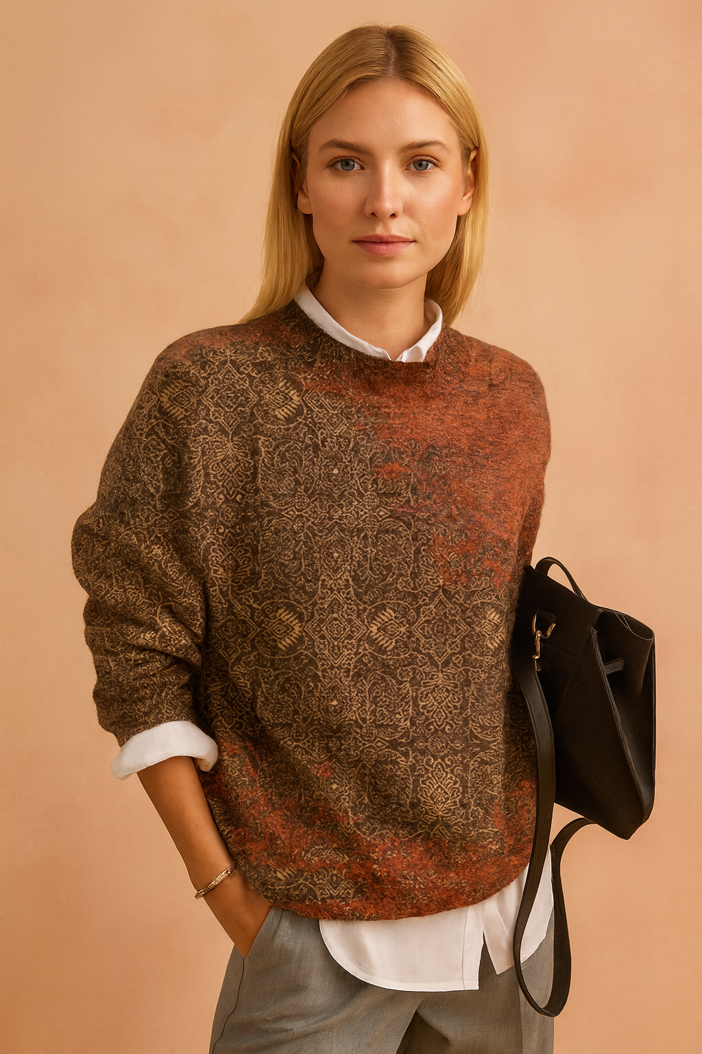 Patterned wool-blend sweater in earthy brown and rust tones with intricate motifs, worn over a crisp white collared shirt and paired with light grey tailored trousers.