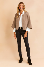  Beige cropped cardigan with a soft, textured finish, worn over a crisp white button-down shirt, paired with high-waisted dark skinny jeans and black suede ankle boots.
