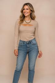 Beige ribbed long-sleeve cutout top paired with high-waisted blue jeans and a chunky gold chain necklace.