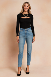 Black ribbed long-sleeve cutout top paired with high-waisted light blue jeans and black pointed-toe pumps, accessorized with a chunky gold chain necklace.