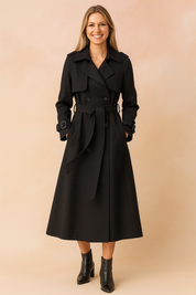 Elegant black double-breasted trench coat with waist belt, calf-length hemline, wide lapels, shoulder epaulets, and adjustable wrist straps, paired with sleek black ankle boots.