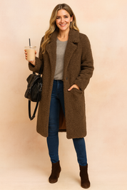 Dark brown teddy coat with a soft textured finish, worn over a light grey knit top and paired with dark blue skinny jeans and brown suede ankle boots, accessorized with a black leather backpack.