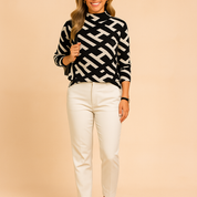 Black and beige geometric-patterned long-sleeve sweater paired with cream tailored pants and black heels