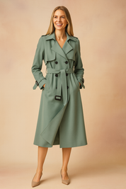 Elegant sage green double-breasted trench coat with matching belt, long sleeves with buckle straps, and a classic knee-length A-line silhouette, paired with beige pointed-toe pumps.