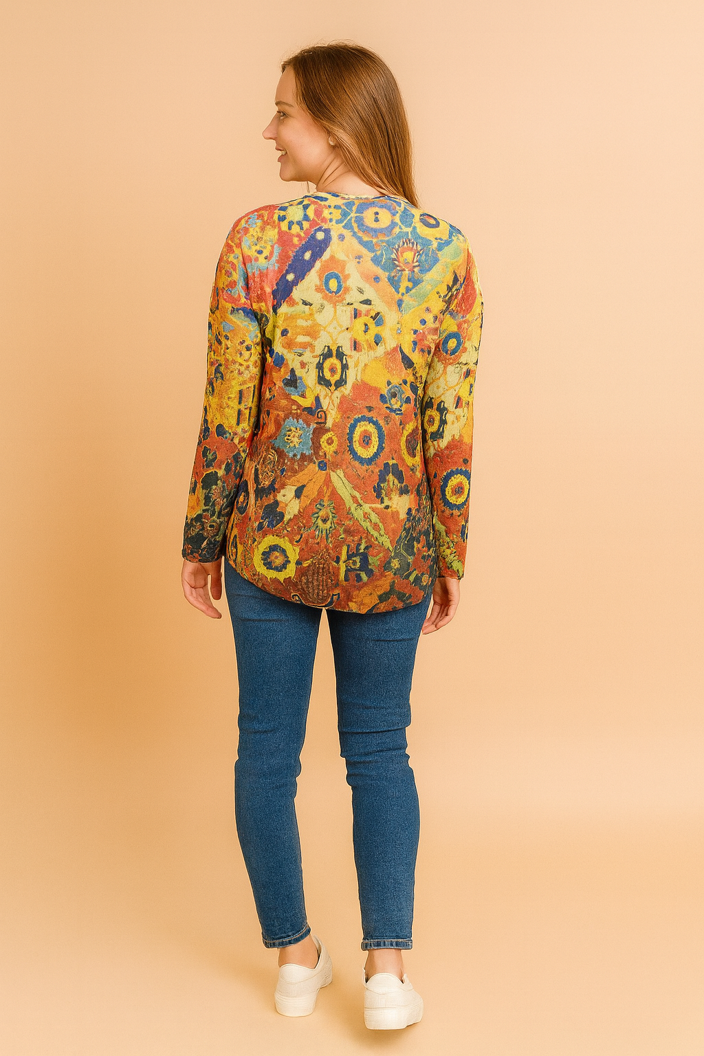 Vibrant long-sleeve top with a multicolor Moroccan-inspired geometric and floral pattern, paired with fitted blue denim jeans and white slip-on sneakers, viewed from the back.