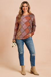 Colorful long-sleeve printed sweater featuring a woven-style pattern in red, purple, orange, green, and blue tones, paired with distressed blue jeans and beige ankle boots.