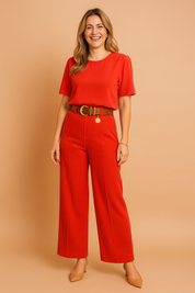 Elegant red two-piece coord set featuring a cropped short-sleeve blouse and high-waisted wide-leg trousers, styled with a chunky brown belt and gold medallion detail.