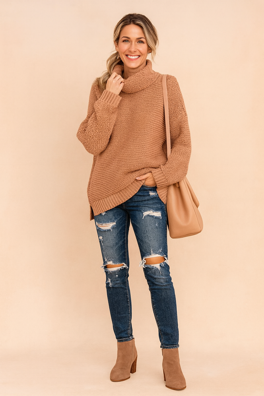 Oversized camel knit turtleneck sweater with textured stitching, paired with distressed skinny blue jeans, taupe ankle boots, and a matching camel shoulder bag.