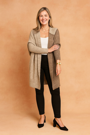 Cozy open-front color block knit cardigan in beige and taupe with ribbed sleeves, paired with a white ribbed tank top and fitted black trousers, completed with black block-heel pumps and a gold wristwatch.