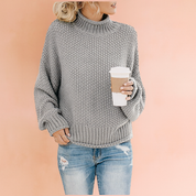 Gray chunky knit turtleneck sweater with textured honeycomb pattern, paired with distressed light blue jeans.