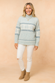 Light blue and white Nordic-patterned knit sweater with high neck, paired with slim white ripped-knee jeans and tan suede ankle boots.