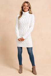White cable-knit turtleneck sweater dress paired with slim-fit blue jeans and taupe suede ankle boots.