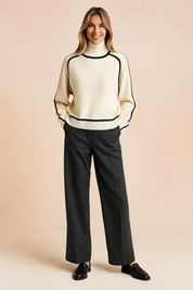 Cream turtleneck sweater with black piping details, paired with wide-leg charcoal trousers and black leather loafers.