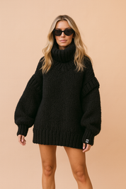 Oversize’owy golf z grubego dziania w kolorze czarnym z obniżonymi ramionami, bufiastymi rękawami i głębokimi ściągaczami przy mankietach i u dołu.