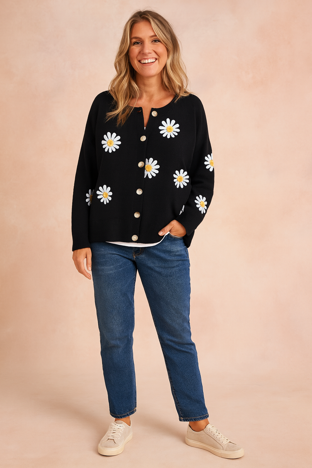Black button-up cardigan with white daisy prints over a white inner top, paired with straight-leg blue jeans and beige sneakers.