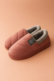 Donkerroze gewatteerde herenpantoffels met grijze fleece voering op een beige achtergrond
