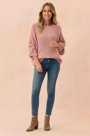 Dusty pink oversized knit sweater with ribbed cuffs and hem, paired with fitted blue jeans and taupe suede ankle boots.

