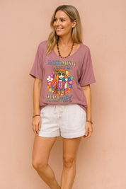 Loose dusty rose statement graphic t-shirt with floral design, paired with high-waisted white drawstring linen shorts.