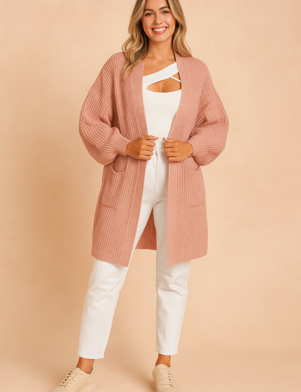 Dusty rose pink ribbed knit open-front cardigan with long sleeves, front patch pockets, styled over a white top and white trousers with beige sneakers.