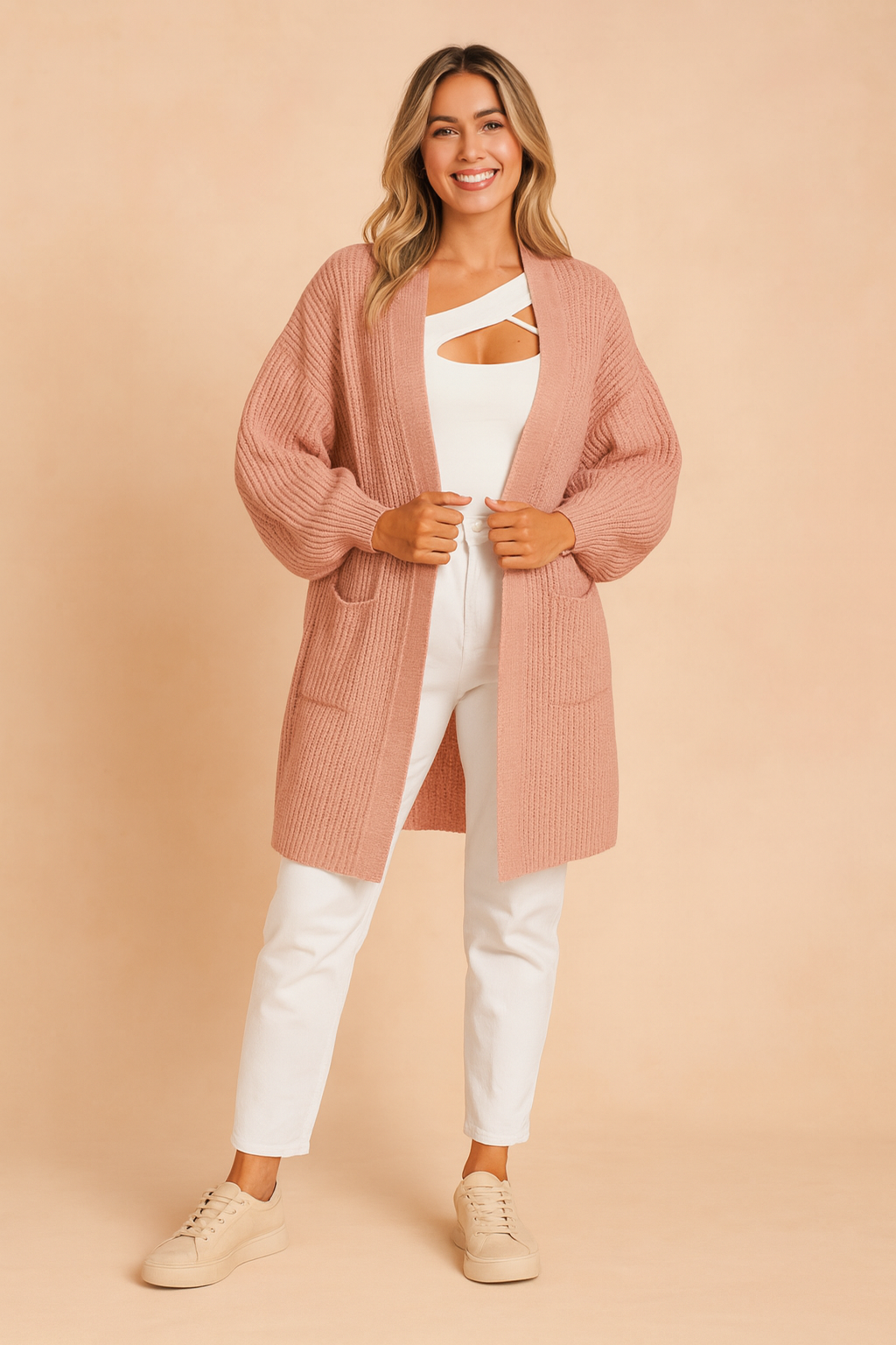Dusty rose pink ribbed knit open-front cardigan with long sleeves, front patch pockets, styled over a white top and white trousers with beige sneakers.