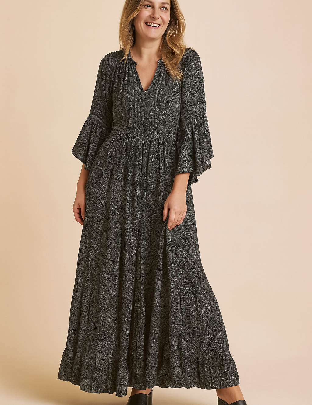Long-sleeve charcoal paisley maxi dress with flared cuffs, V-neckline, tiered ruffle hem, and soft boho-inspired silhouette.