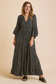 Long-sleeve charcoal paisley maxi dress with flared cuffs, V-neckline, tiered ruffle hem, and soft boho-inspired silhouette.